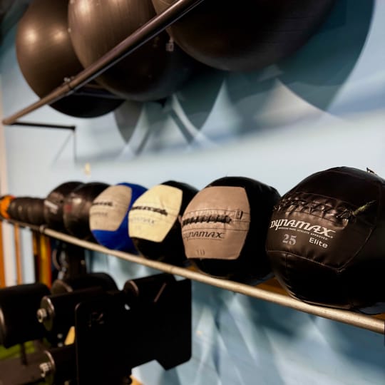 Medicine balls and wall balls racked along the studio wall.
